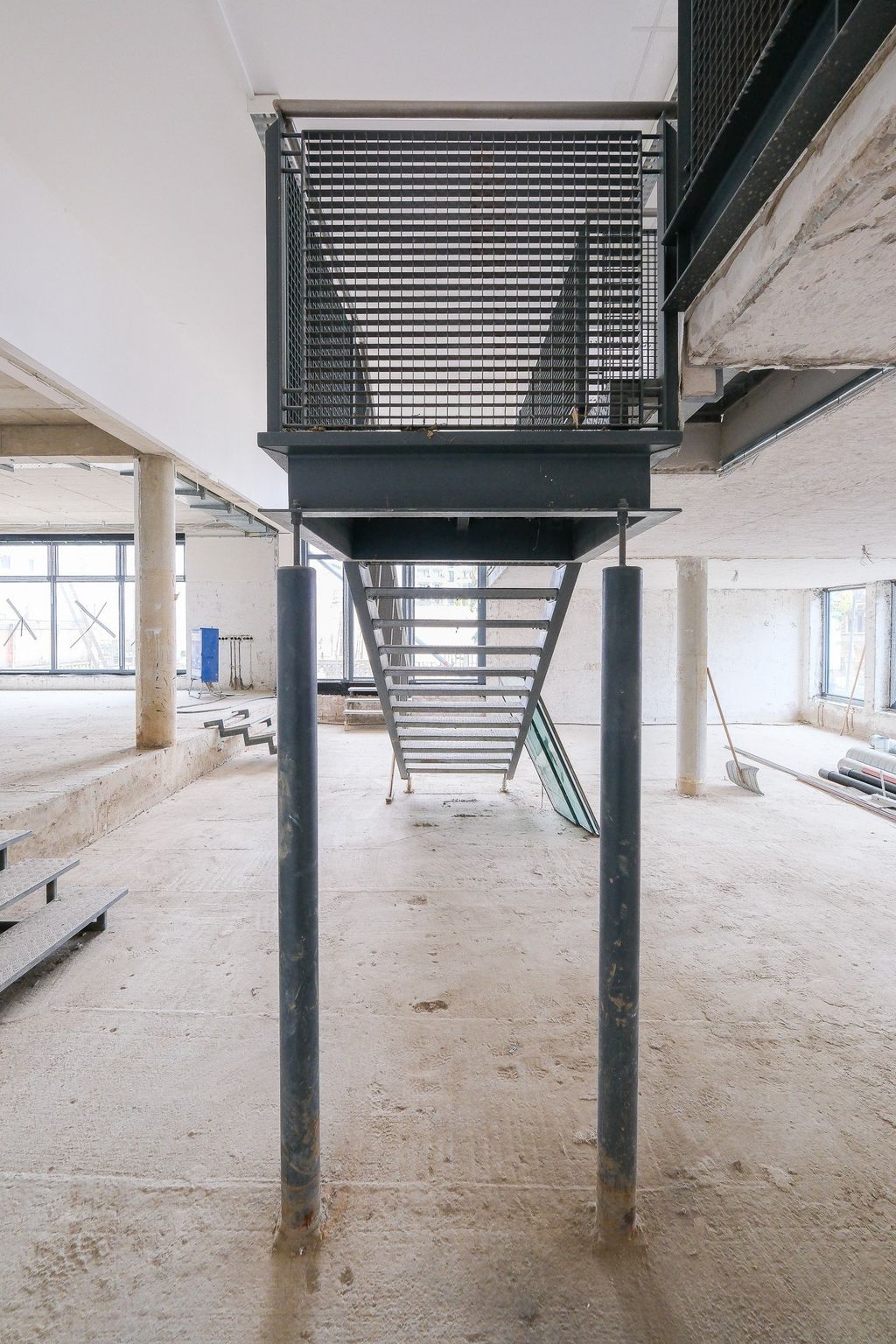 Industrielle Metalltreppe in einem großen, unfertigen Innenraum mit Betonboden und Säulen.