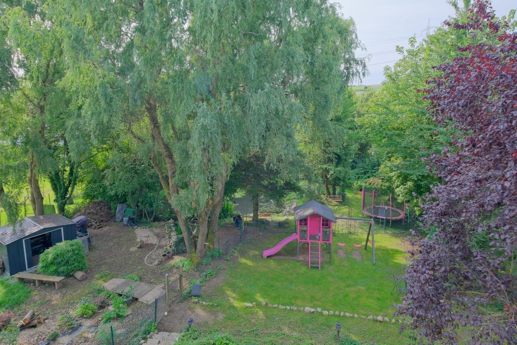 Ein Spielplatz mit einer Kletterstruktur in Pink mit Rutsche und Schaukel neben einem Trampolin, umgeben von Bäumen und Grünflächen in einem Garten.