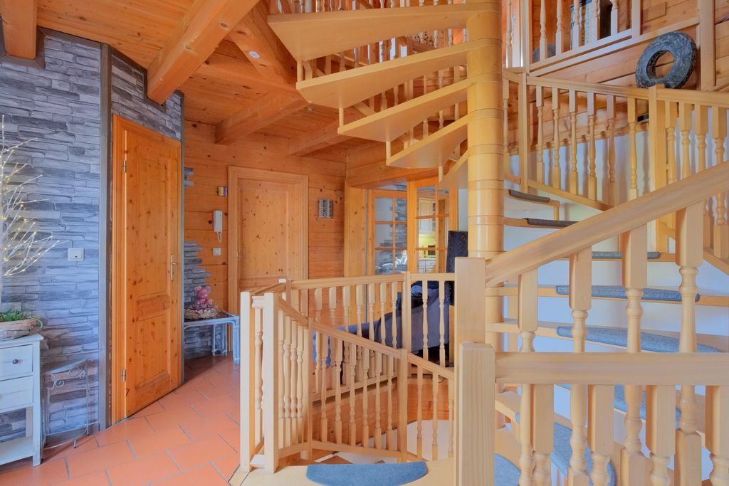 Heller, gemütlicher Innenraum mit einer Wendeltreppe aus hellem Holz und einer Tür mit steinverkleideter Wand.