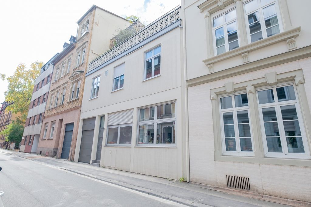 Reihe von mehrstöckigen Wohngebäuden an einer ruhigen Straße mit Bürgersteig und Baum am Straßenrand.