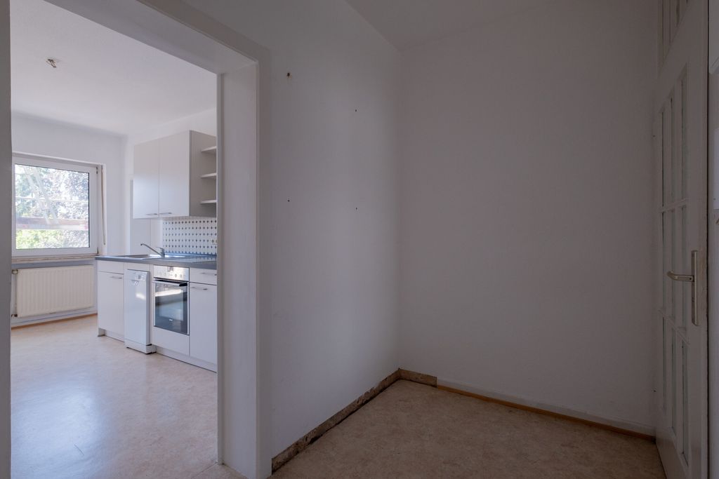 Leere Eingangshalle mit Blick in eine weiße Küche mit Ofen, Spüle und Fenster, natürlichem Licht.