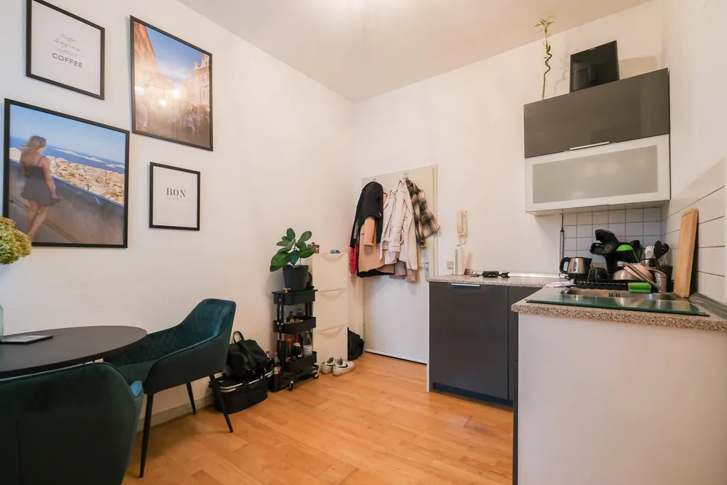 Moderner Eingangsbereich einer Wohnung mit Garderobe, Pflanzen, Getränkekühlschrank und einigen gerahmten Bildern an der Wand.